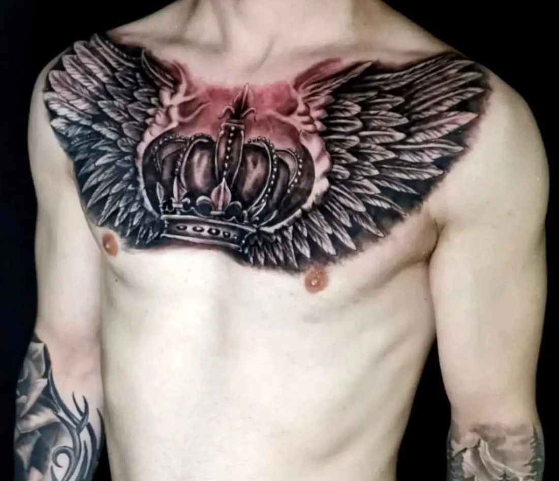 Crown and wings chest tattoo in black and grey realism, by Scorpion Ink
