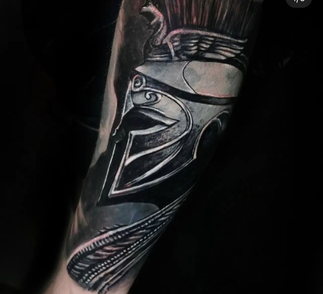 Realism Spartan helmet tattoo in black and grey on a leg, by Scorpion Ink
